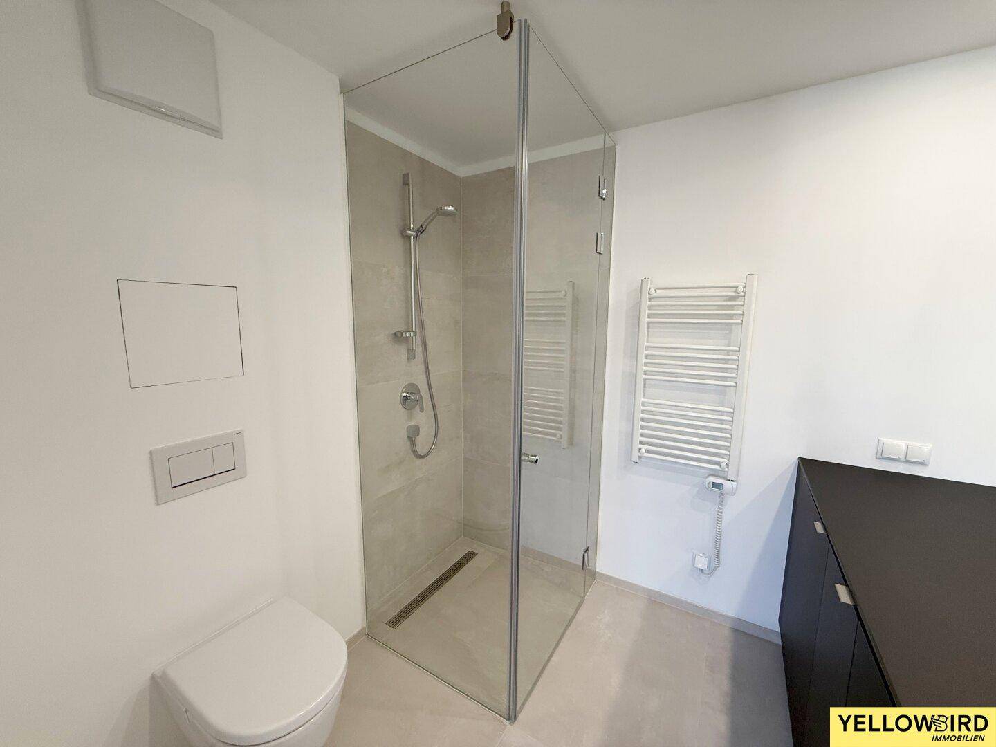Zeitgemäßes Badezimmer mit begehbarer Dusche, wandhängendem WC und praktischem Handtuchheizkörper.