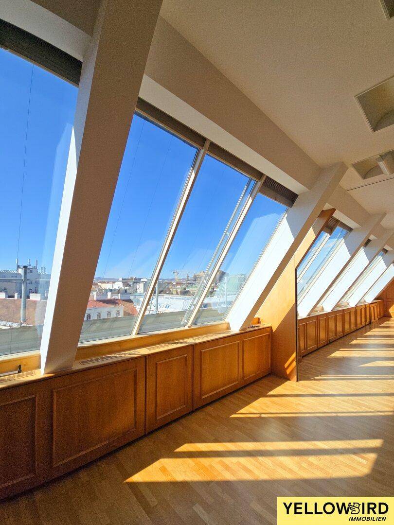 Detailansicht der schrägen Fensterfront und der eleganten Holzvertäfelung, die den Raum charakterisiert.