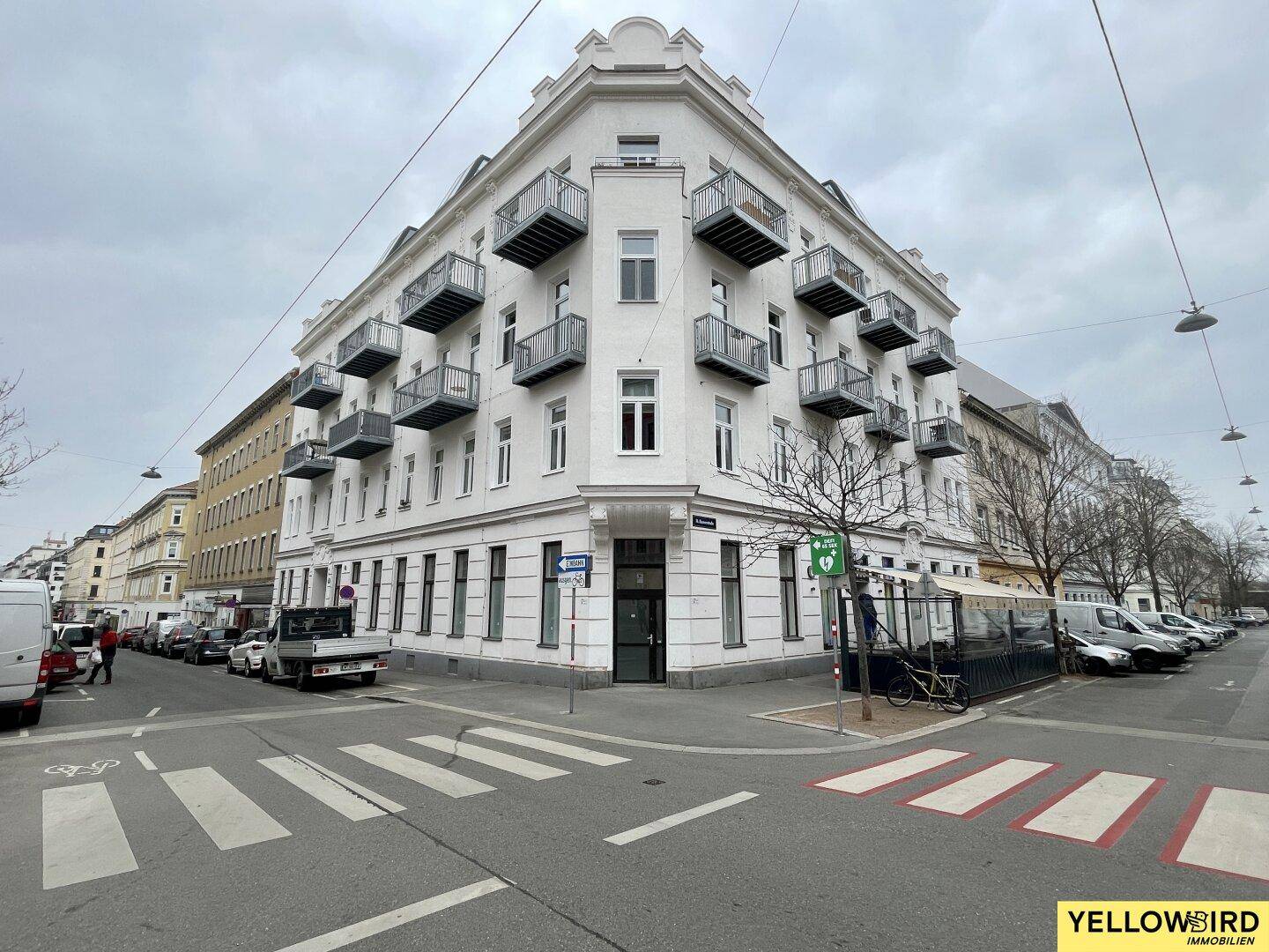 Eckgebäude mit vielen kleinen Balkonen und einer modernen Architektur in städtischer Umgebung.