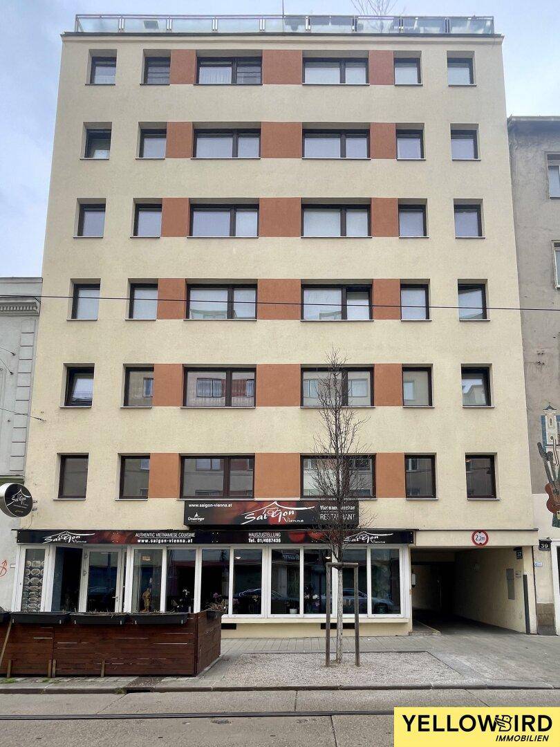 Modernes Gebäude mit Restaurant im Erdgeschoss und Wohnungen darüber in einer städtischen Straße.