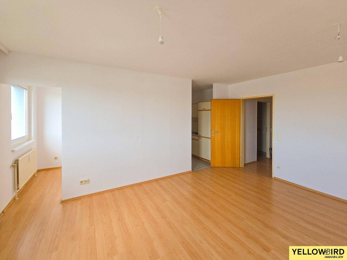 Geräumiger, heller Wohnbereich mit Parkettboden und Zugang zu weiteren Räumen.