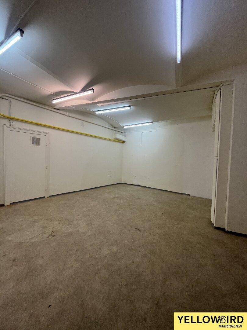 Leerer Raumecke mit Betonboden, weißen Wänden und Deckenbeleuchtung, bereit zur Nutzung.