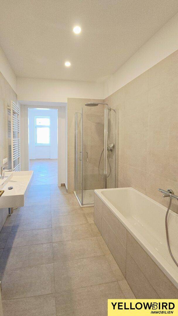 Modernes Badezimmer mit hellgrauen Fliesen, Doppelwaschbecken, begehbarer Dusche und Badewanne.