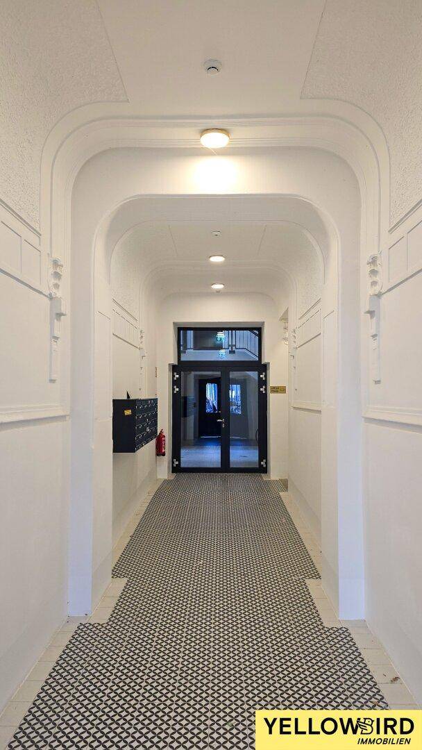 Repräsentativer Eingangsbereich mit gemustertem Fliesenboden und Zugang zum Treppenhaus.