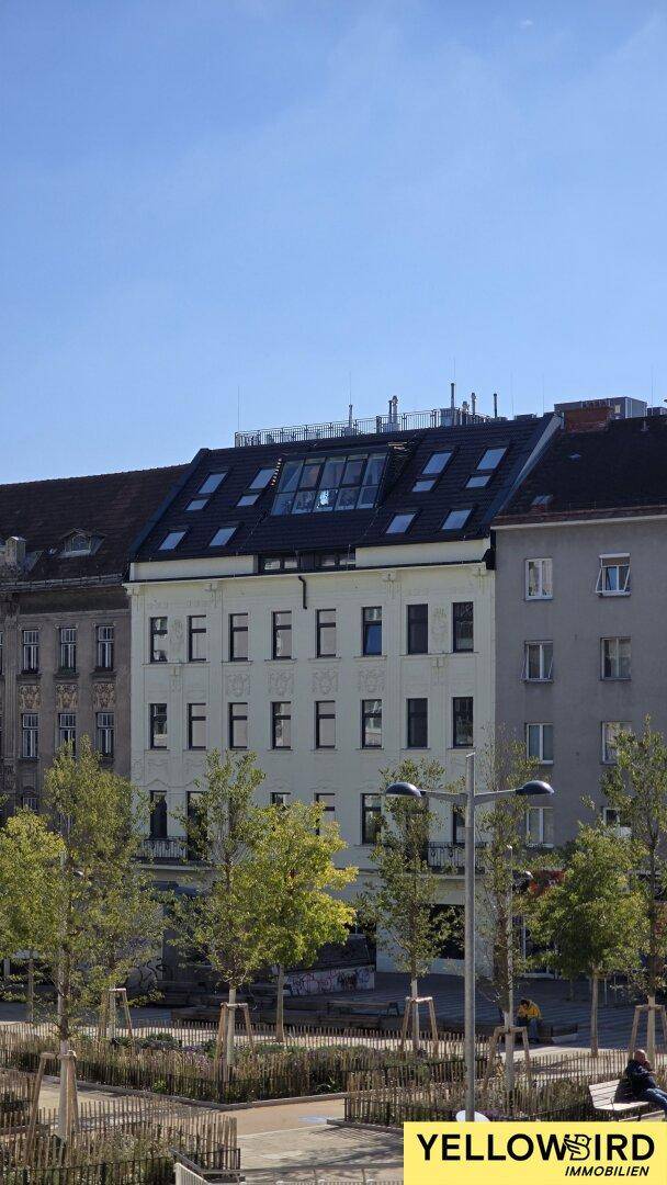 Historisches Gebäude mit Mansarddach und vielen Dachfenstern in urbaner Umgebung.