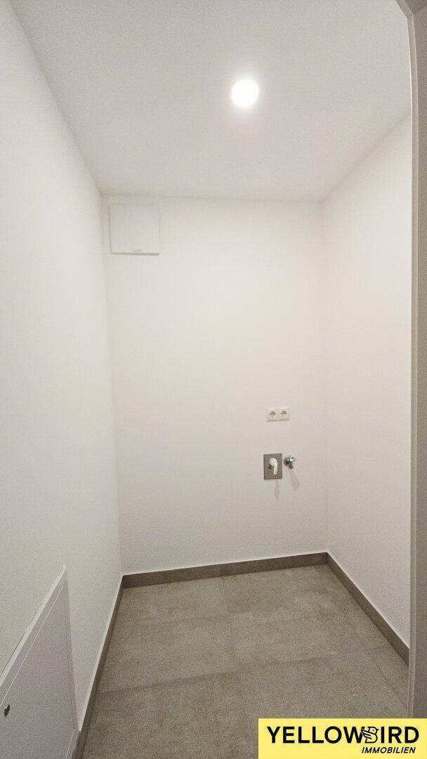 Kleiner Hauswirtschaftsraum mit Fliesenboden und Anschlüssen für Waschmaschine.