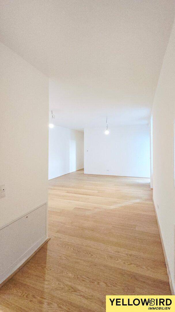 Leerer, heller Raum mit Holzboden und weißen Wänden, bereit zur individuellen Gestaltung.