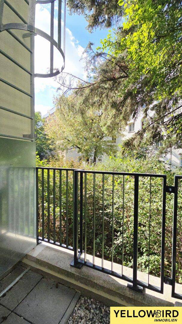 Balkon mit Metallgeländer und üppigem Grünblick, ideal zum Entspannen im Freien.