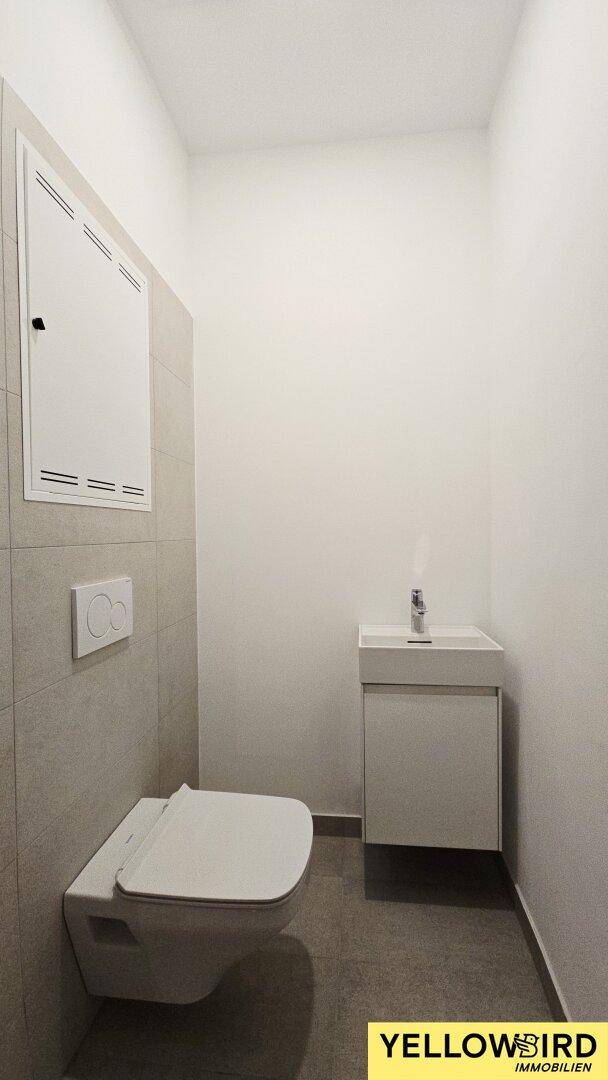 Modernes Gäste-WC mit wandhängender Toilette und kleinem Waschbecken.