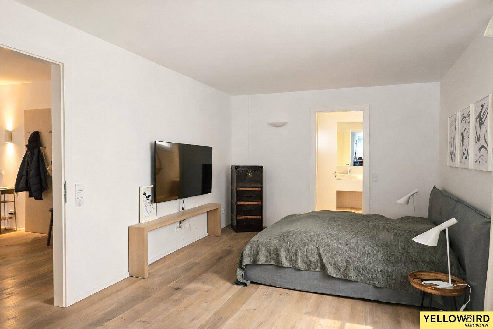 Geräumiges Schlafzimmer mit Holzboden und direktem Zugang zum modernen Badezimmer.