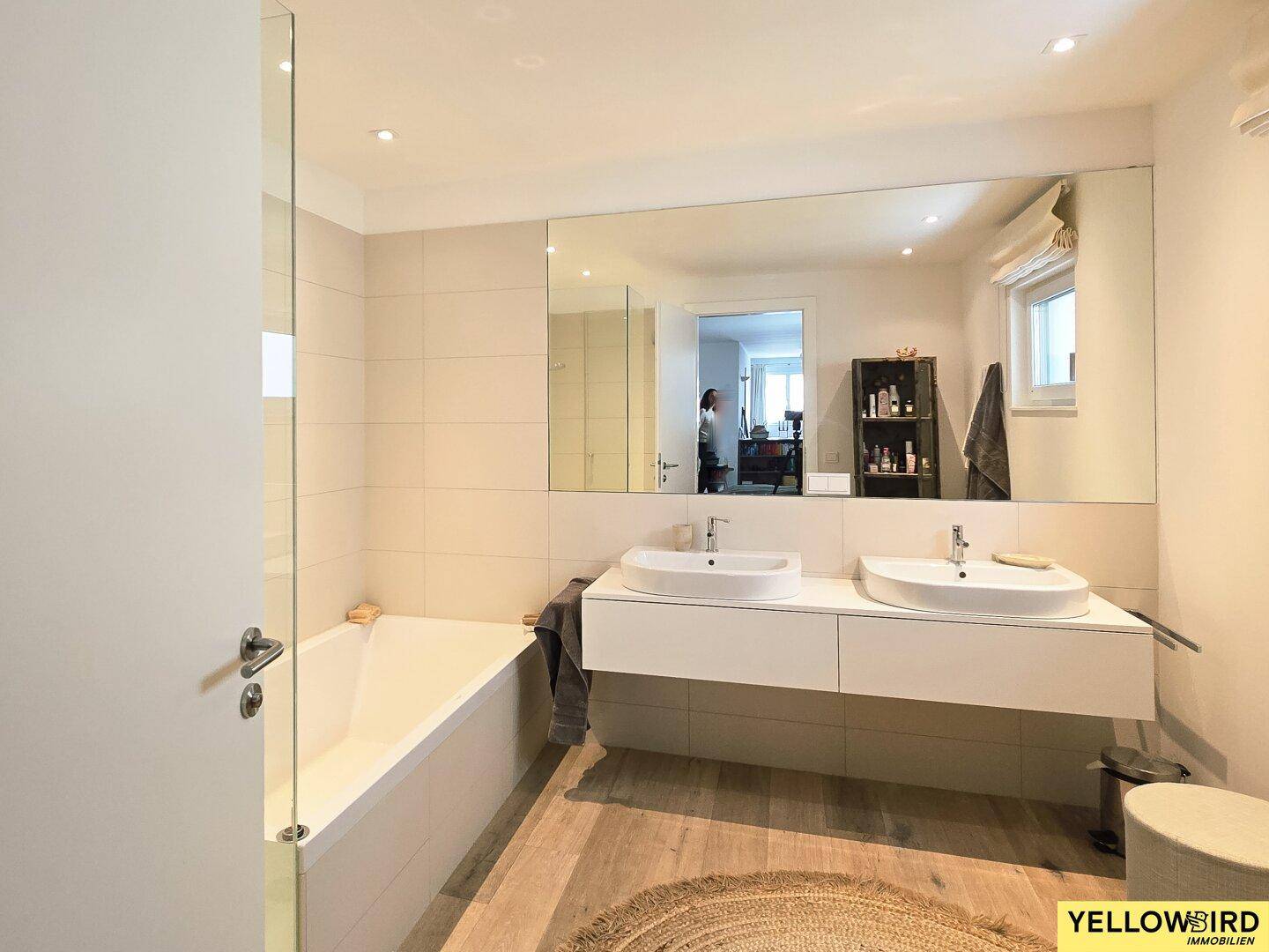 Geräumiges Badezimmer mit Doppelwaschbecken, Badewanne und großem Spiegel, bietet viel Komfort.