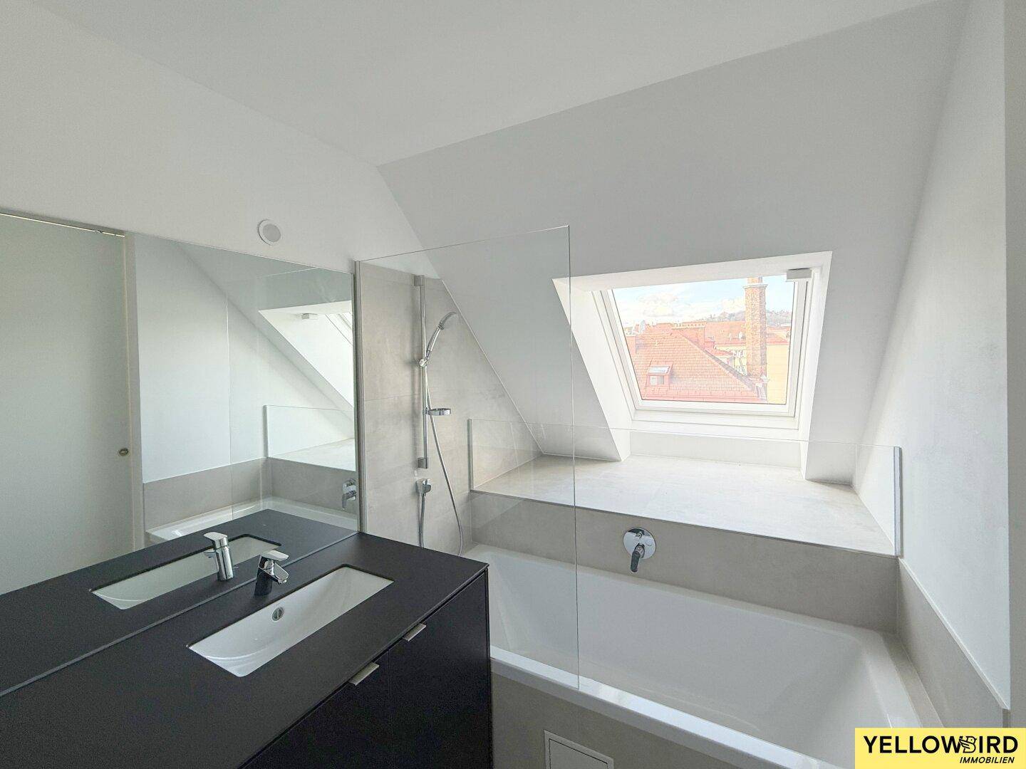 Modernes Badezimmer mit Badewanne, Dachfenster und dunklem Waschtischunterschrank.