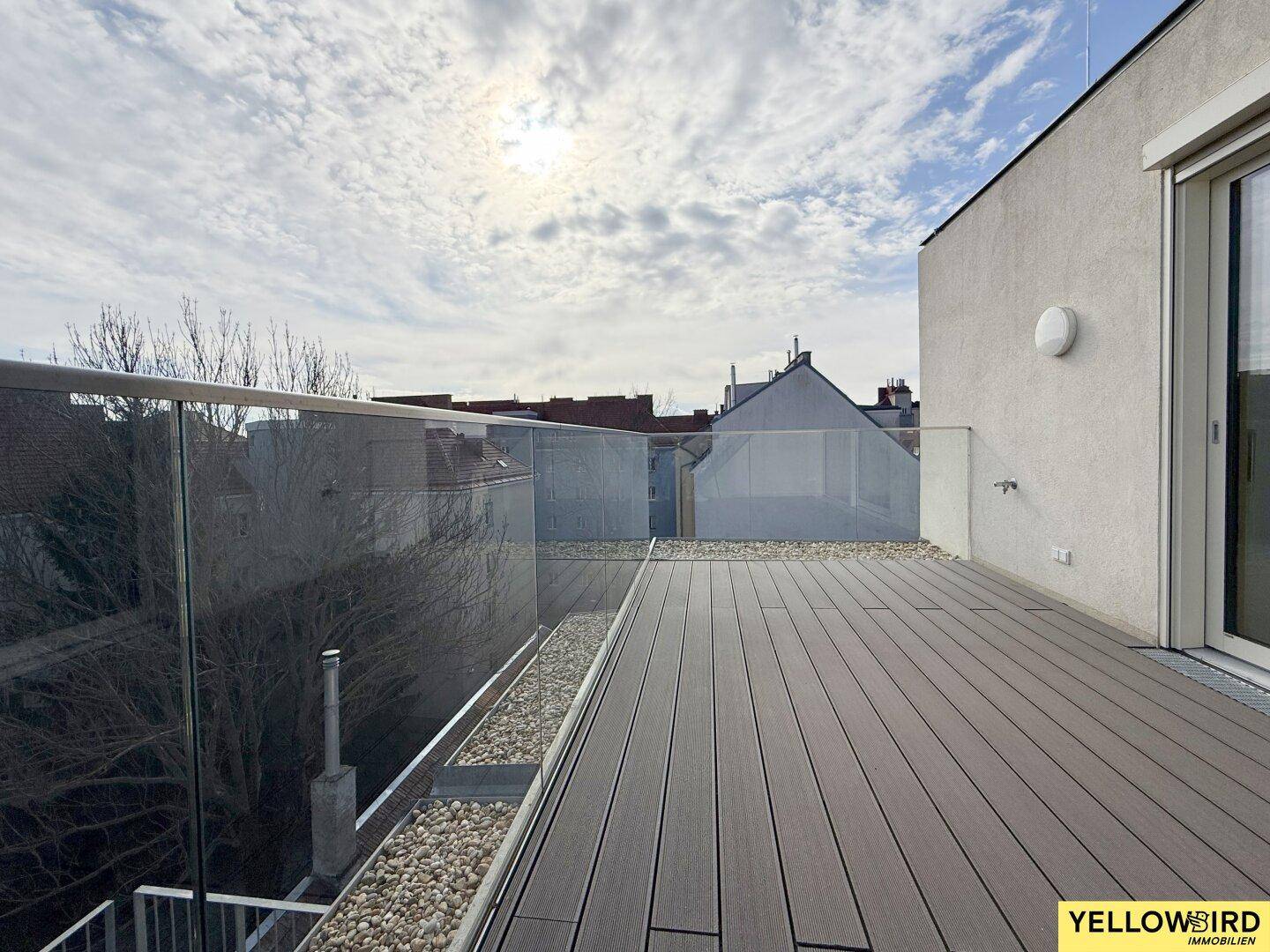 Geräumige Dachterrasse mit Holzdielenboden und Glasgeländer, bietet einen weiten Blick.