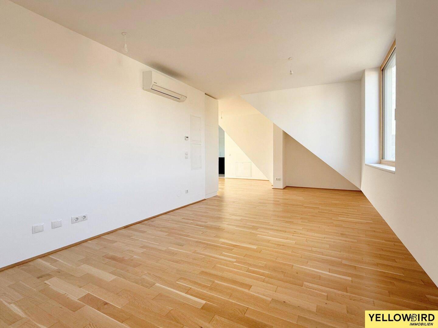 Geräumiger, heller Wohnraum mit Holzboden und Klimaanlage, ideal für individuelle Gestaltung.
