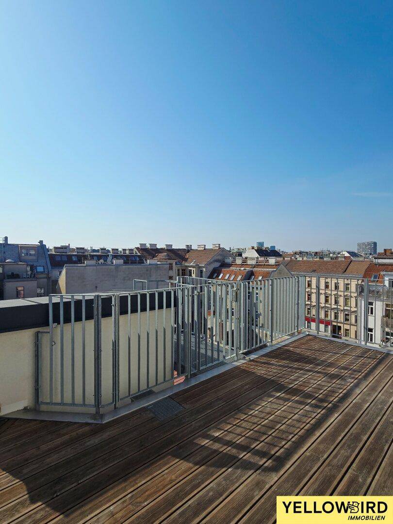 Geräumige Dachterrasse mit Holzboden und weitem Blick über die Dächer der Stadt.