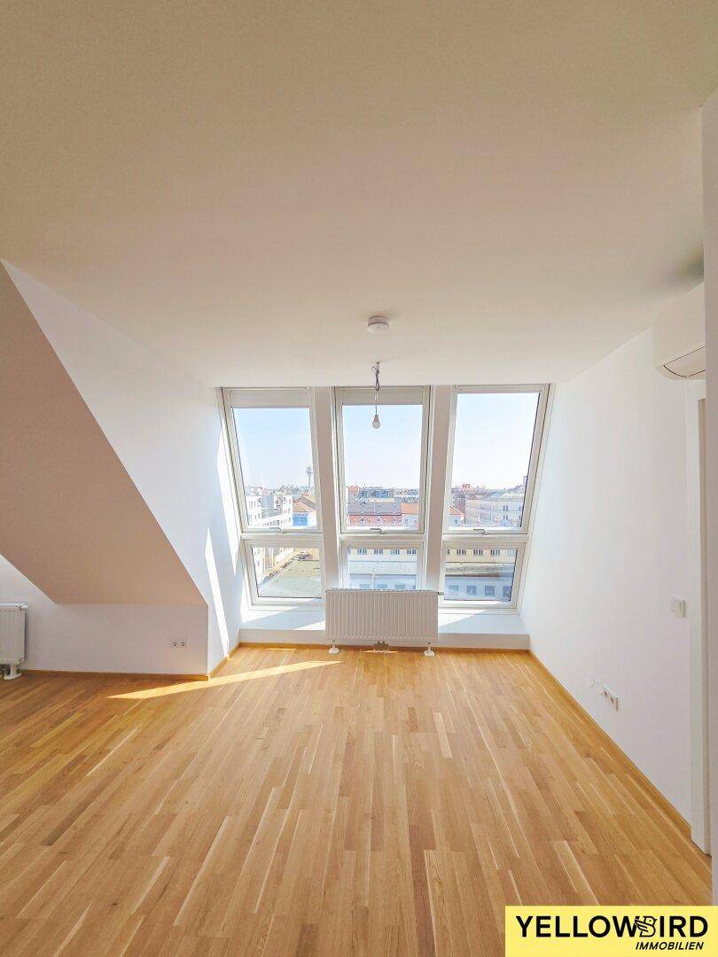 Lichtdurchfluteter Raum mit Holzboden und großer Fensterfront mit Blick über die Stadt.
