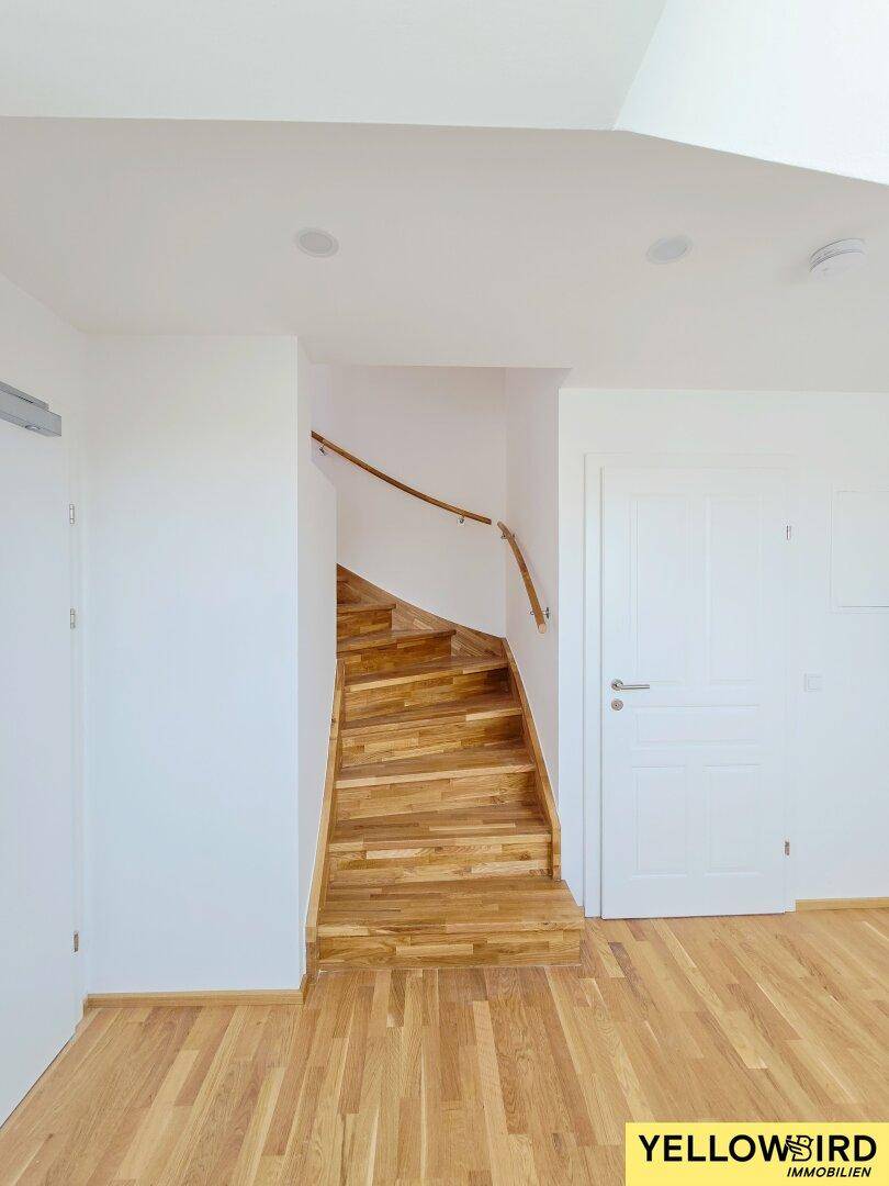 Elegante Holztreppe mit passendem Handlauf, die in die obere Etage führt.