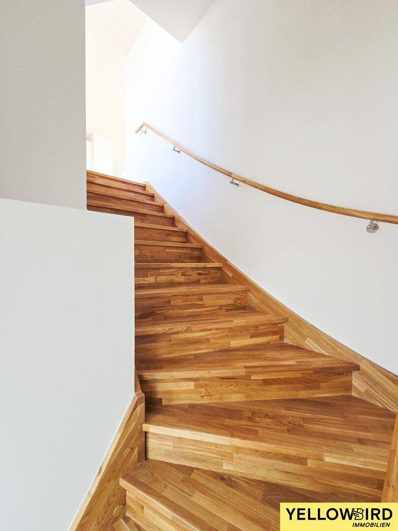 Detailansicht der hochwertigen Holztreppe mit geschwungenem Holzhandlauf.