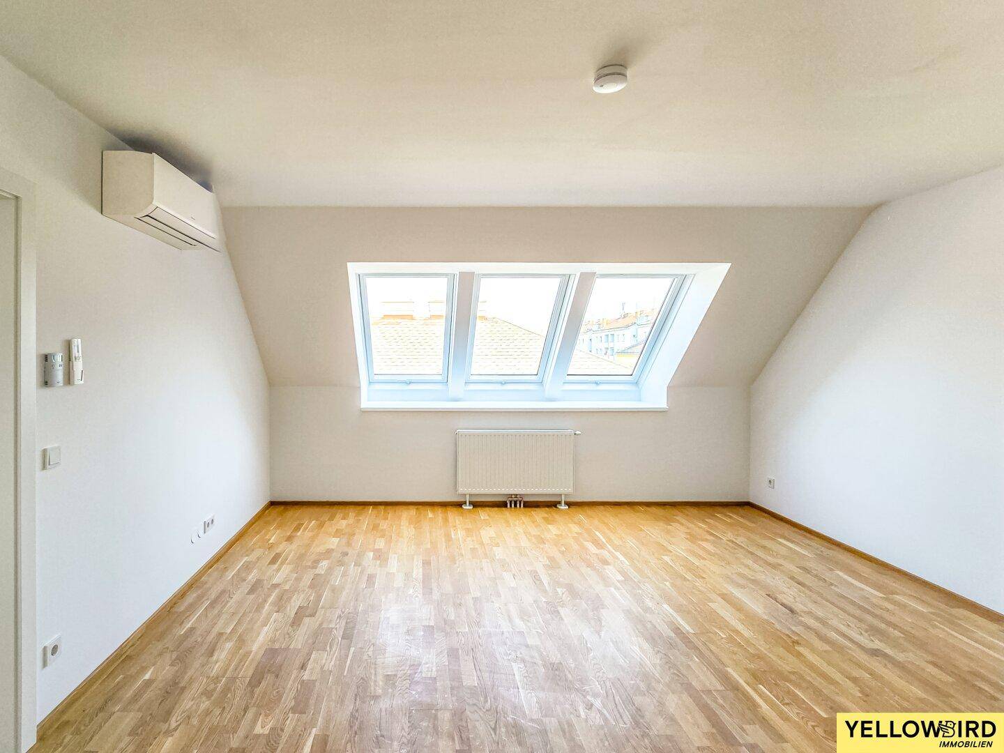 Helles Schlafzimmer im Dachgeschoss mit Holzboden, Dachfenstern und Klimaanlage für angenehmes Klima.