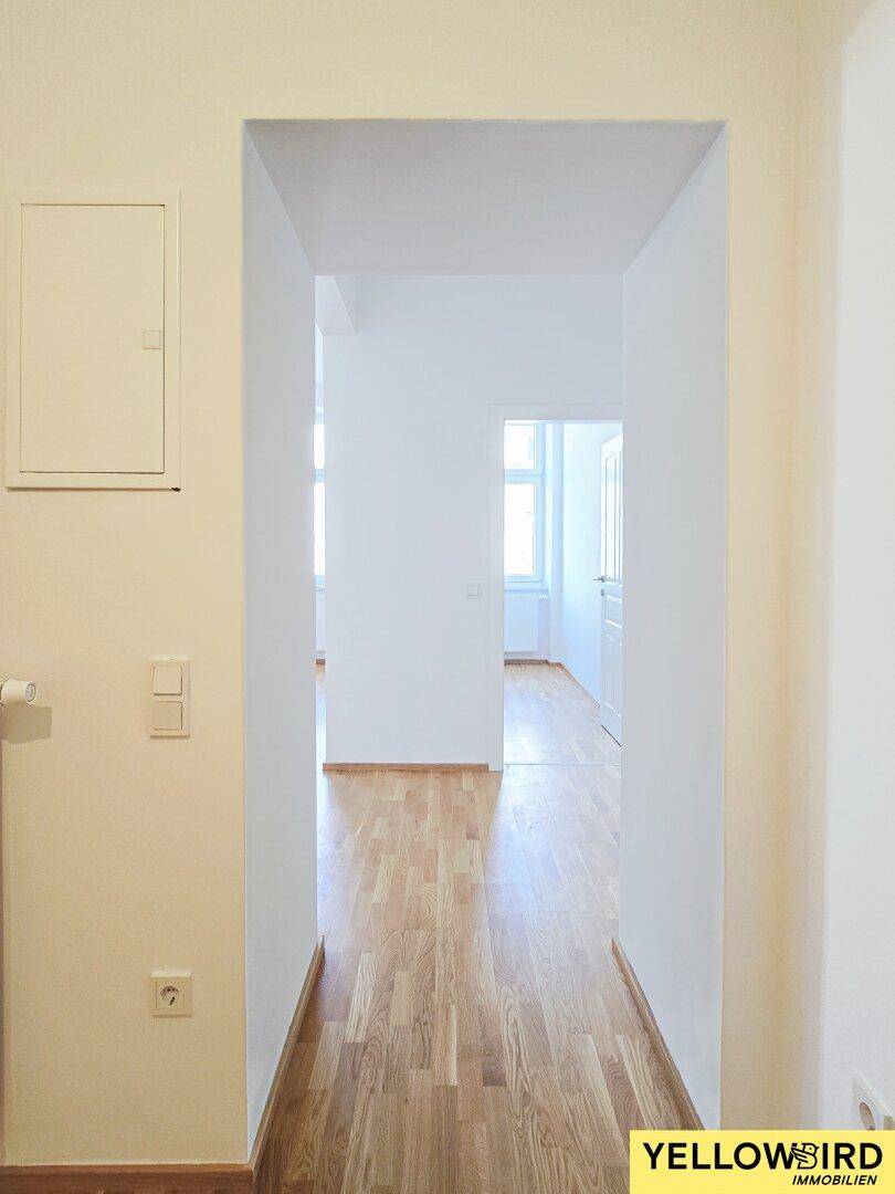Heller Flur mit Parkettboden, der zu weiteren Räumen der Wohnung führt.
