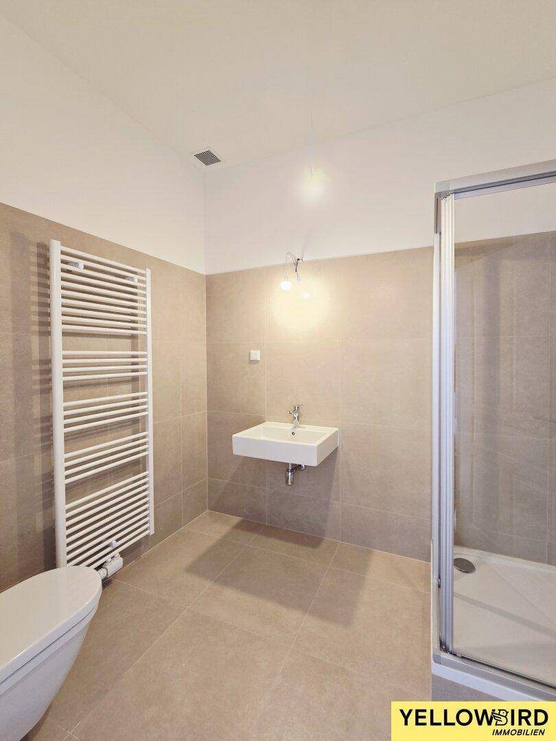 Modernes Badezimmer mit begehbarer Dusche, Wand-WC, Einzelwaschbecken und beheiztem Handtuchhalter.