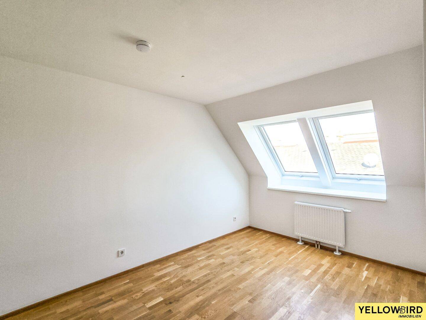 Gemütliches Zimmer im Dachgeschoss mit Holzboden und zwei Dachfenstern, ideal als Kinder- oder Gästezimmer.