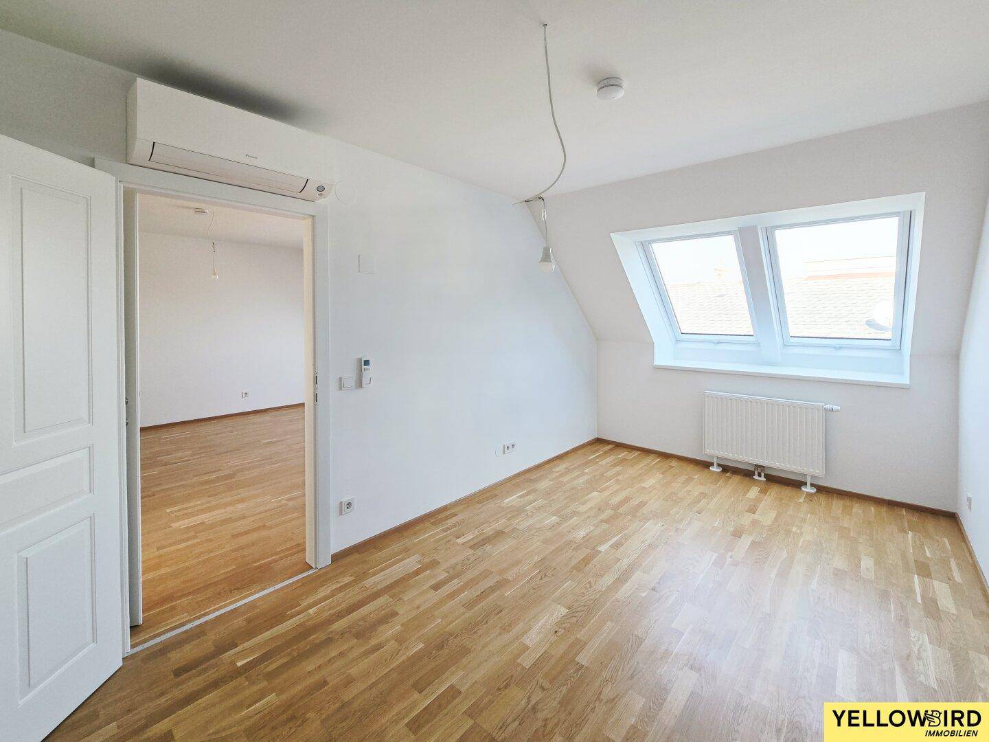 Geräumiges Schlafzimmer mit Holzboden, Dachfenstern und Klimaanlage.