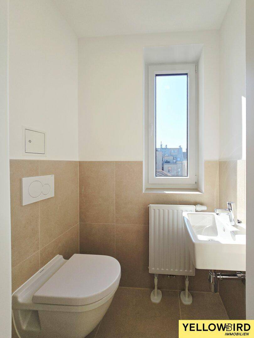 Separate Gästetoilette mit Fenster, Wand-WC und modernem Waschbecken.