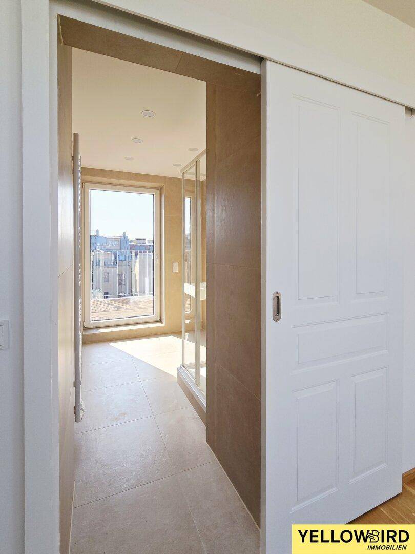 Heller Flur mit Schiebetür, der zu einem modernen Badezimmer mit Fenster führt.