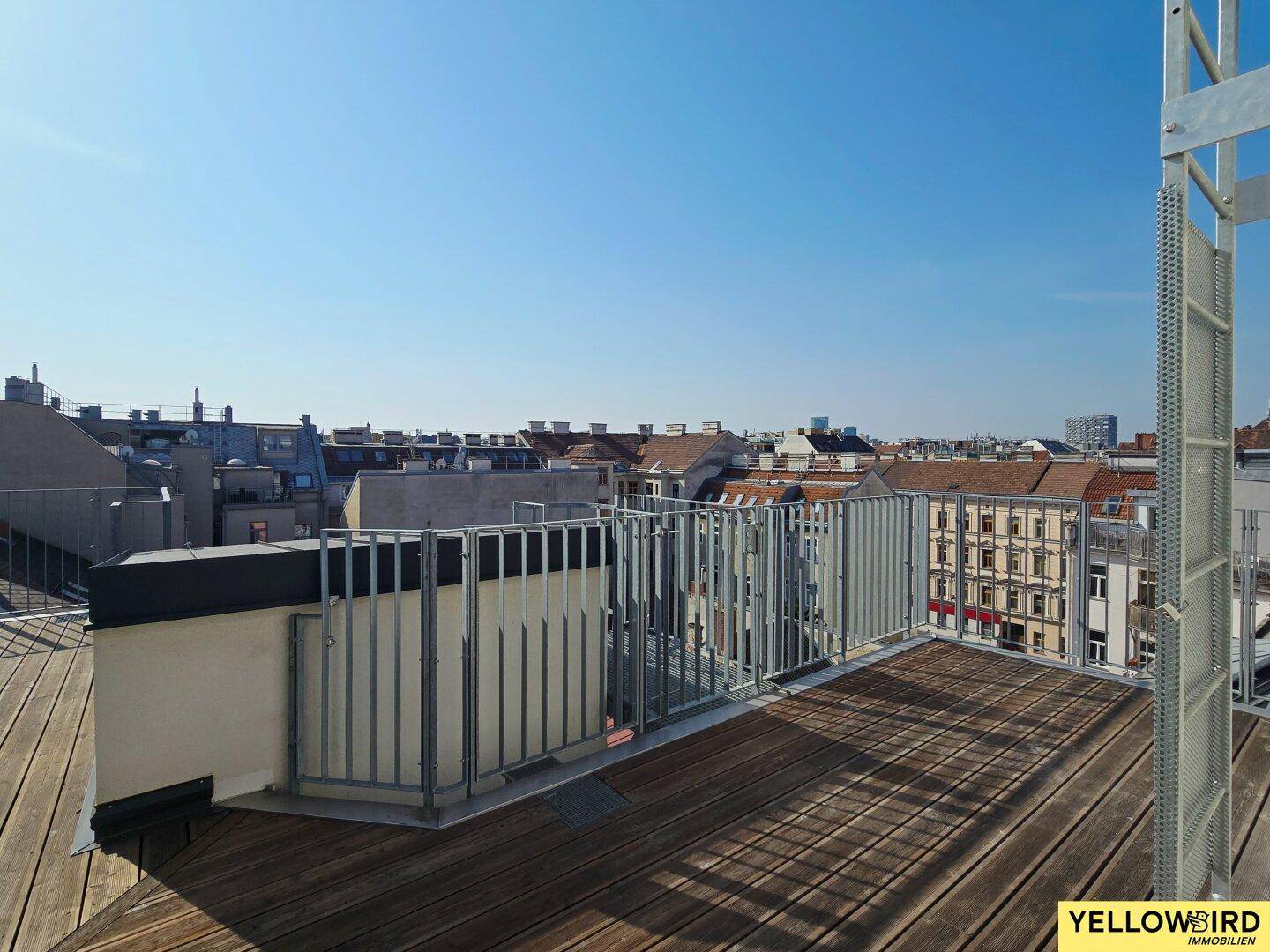Weitläufige Dachterrasse mit Holzboden und Panoramablick über die Stadt.