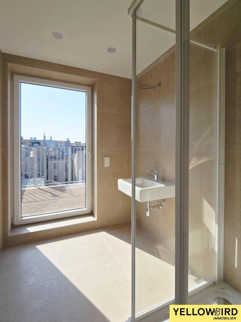 Modernes Badezimmer mit Dusche, Waschbecken, Fliesenboden und Zugang zur Terrasse.