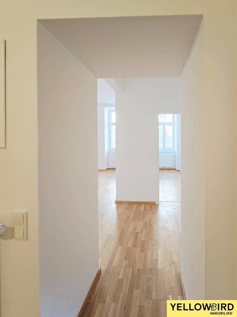 Langer, heller Flur mit Holzparkettboden, der zu weiteren Zimmern der Wohnung führt.