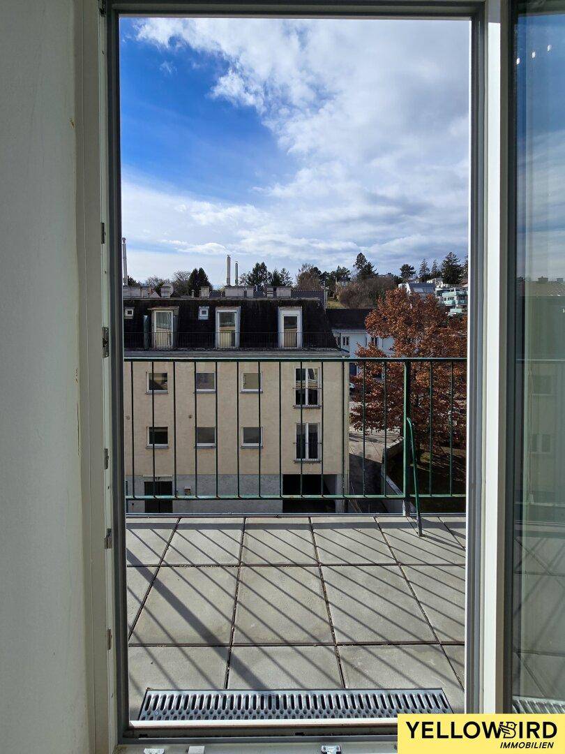 Ausblick vom Balkon auf die umliegenden Gebäude und den blauen Himmel.