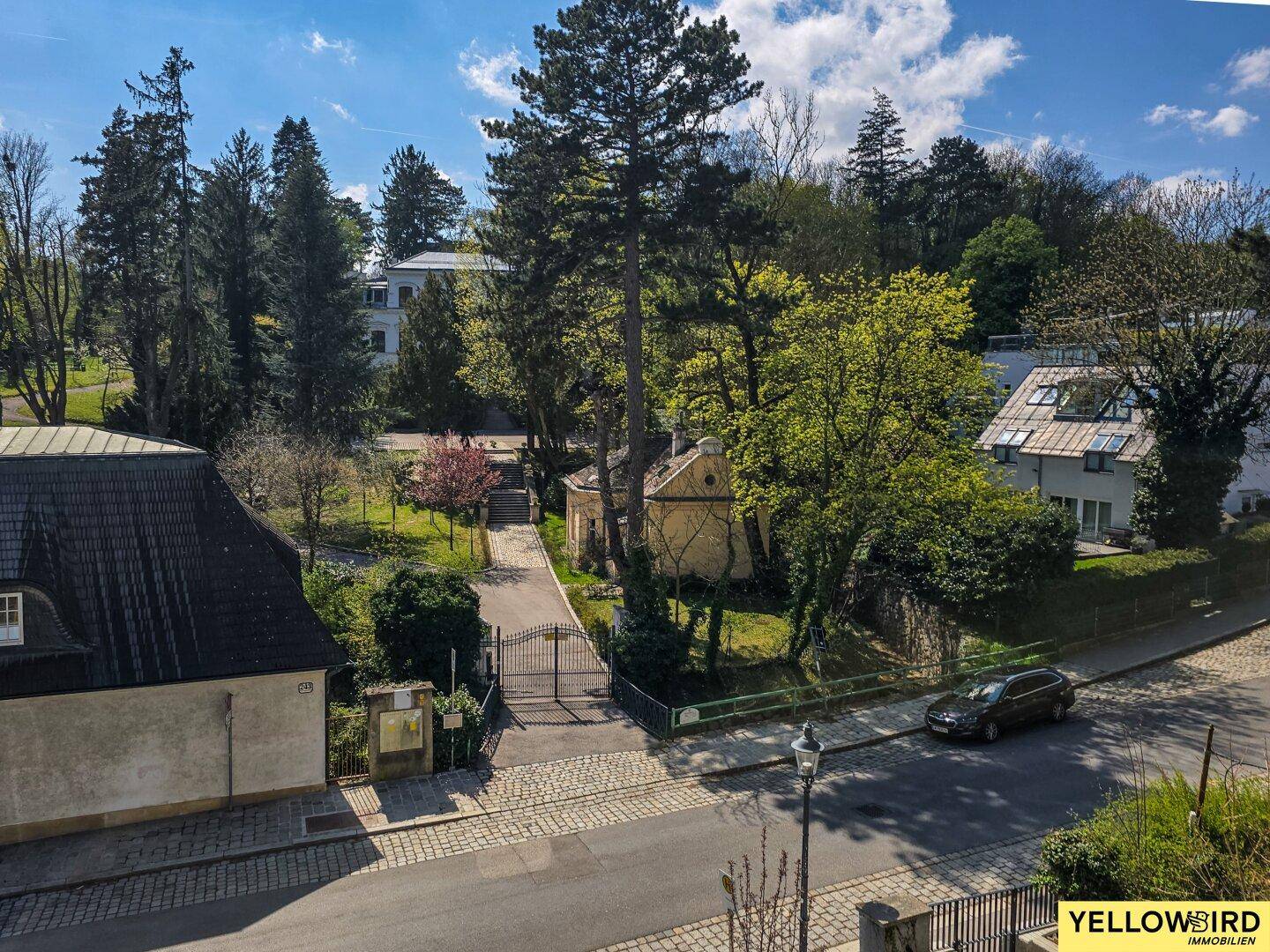 Weitläufige Ansicht der Umgebung mit Bäumen, Straße und weiteren Gebäuden an einem sonnigen Tag.