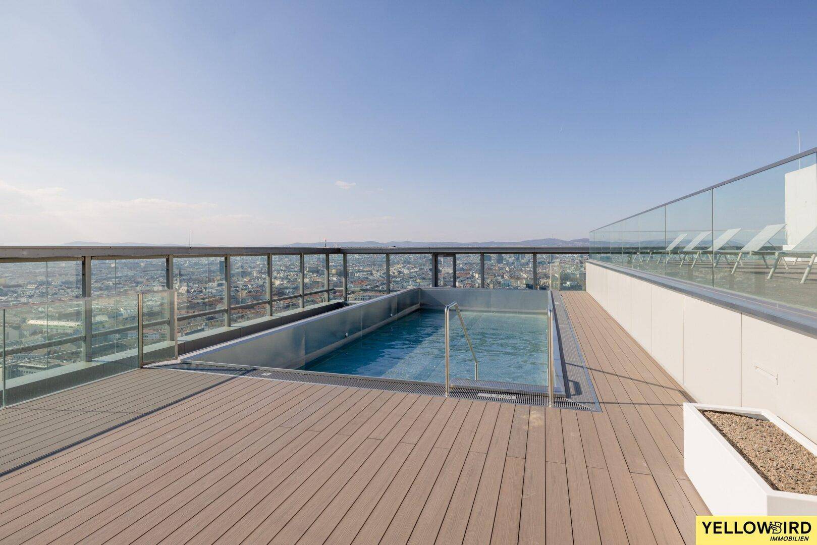 Dachterrasse mit eingelassenem Pool und weitreichendem Blick auf die Stadtkulisse unter klarem Himmel.