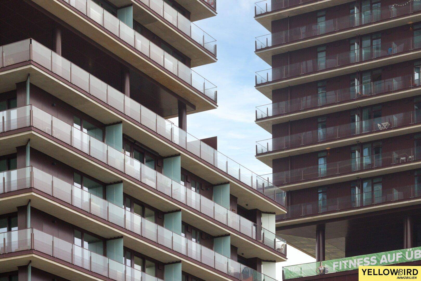 Moderne Architektur mit gestuften Balkonen und Glasbrüstungen an einem Hochhaus.