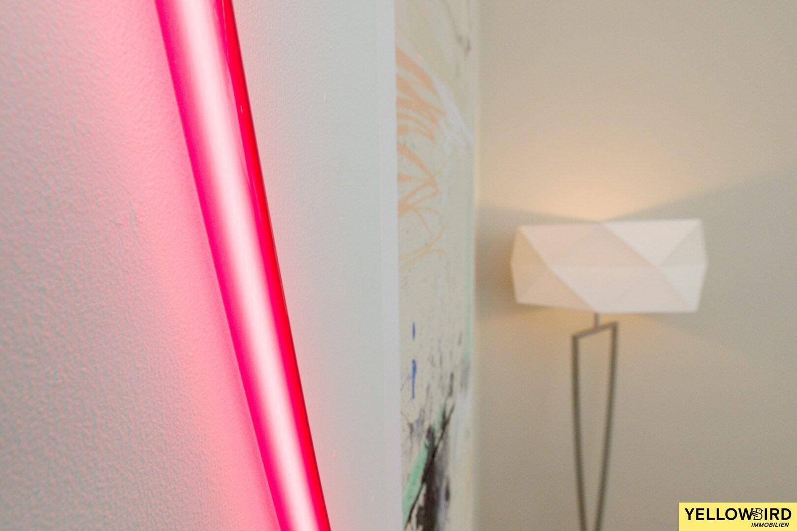 Detailaufnahme einer modernen Wanddekoration mit Neonlicht und Stehlampe.