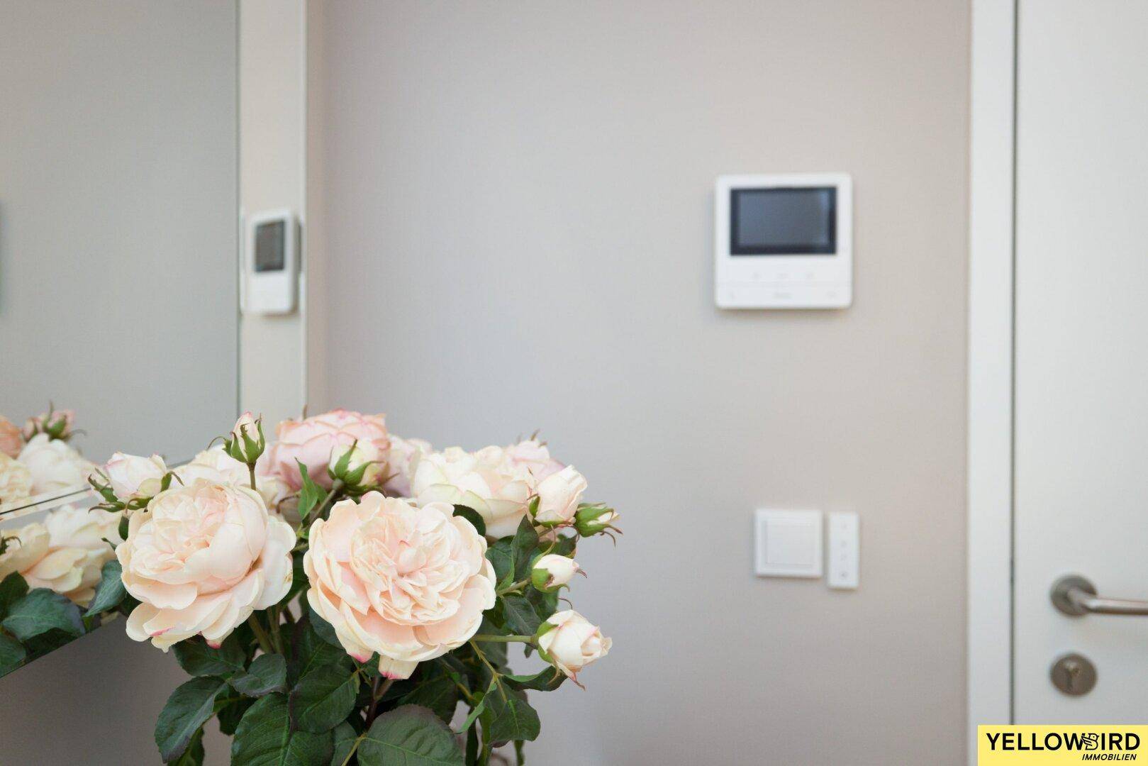 Detailansicht des Eingangsbereichs mit Gegensprechanlage und frischen Blumen.