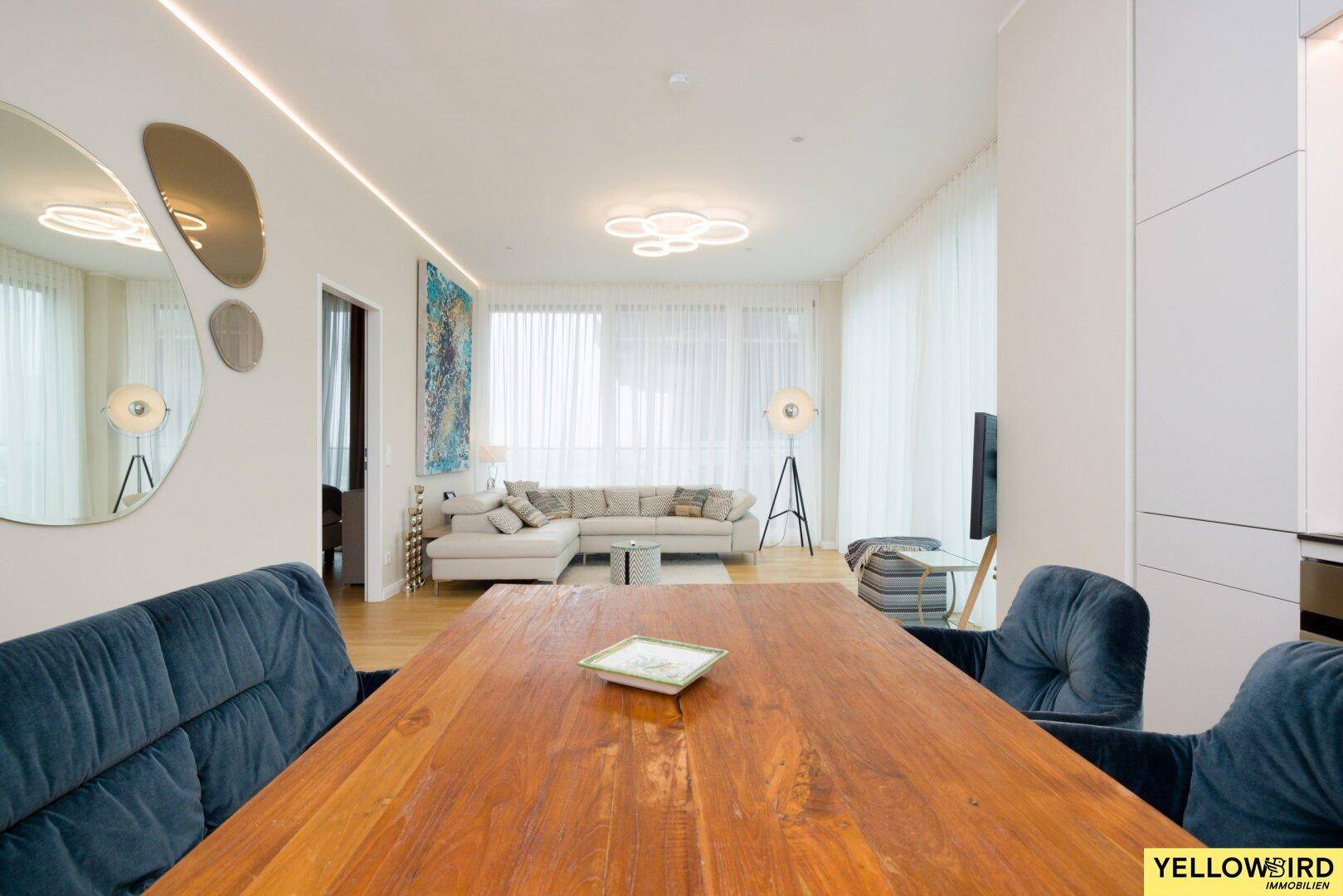 Weitläufiger Wohn-Essbereich mit Holztisch, bequemer Sitzbank und hellem Sofa.