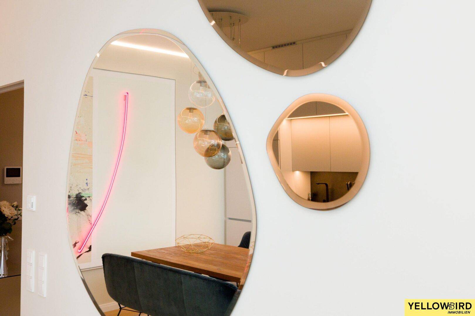 Dekorative Spiegel an der Wand reflektieren den modernen Essbereich und die Küche.