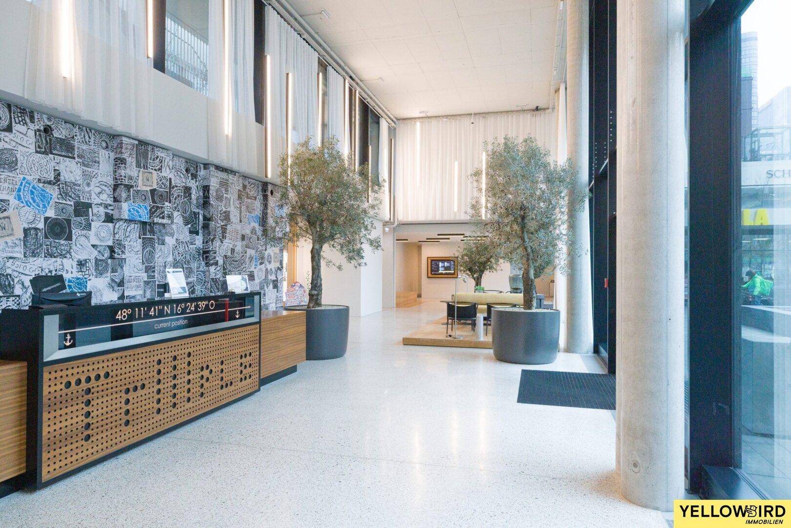 Geräumiger Eingangsbereich oder Lobby mit modernen Möbeln und dekorativen Bäumen.