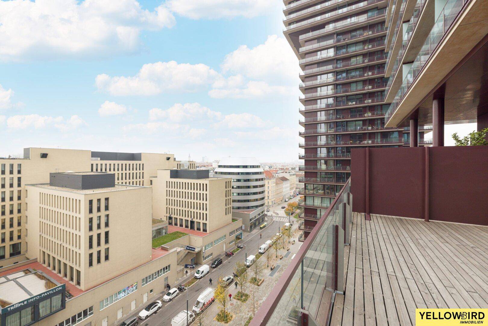 Balkon mit Glasbrüstung bietet einen weiten Blick über die Stadt und umliegende Gebäude.