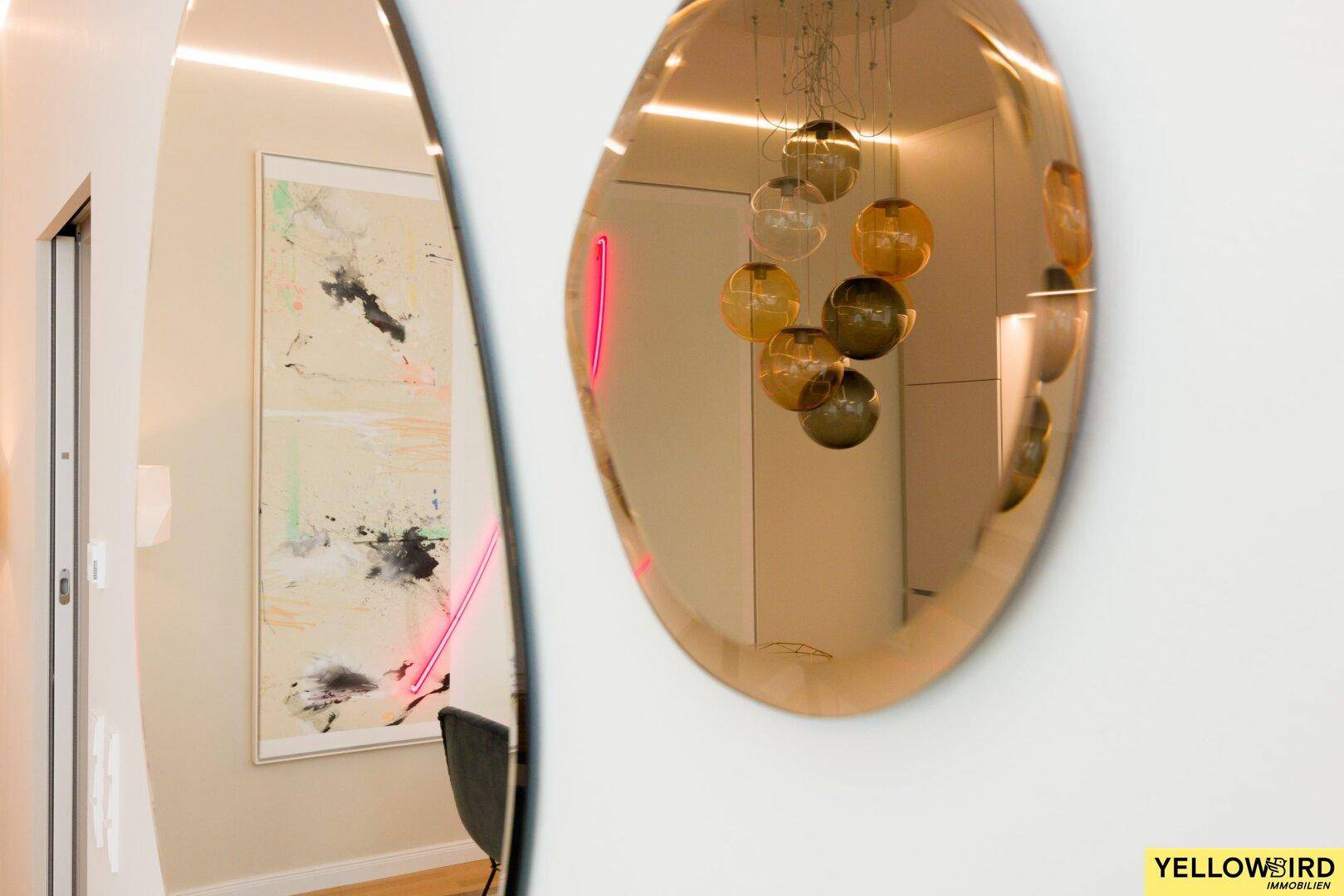 Moderner Flur mit dekorativem Spiegel, Kunstwerk und indirekter Beleuchtung an der Wand.