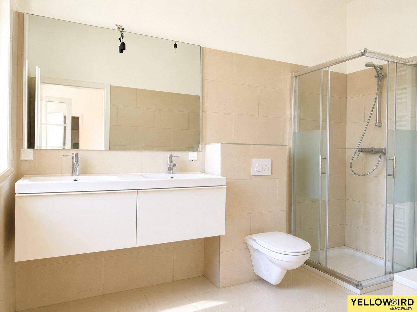 Modernes Badezimmer mit Doppelwaschbecken, Duschkabine und wandhängendem WC.