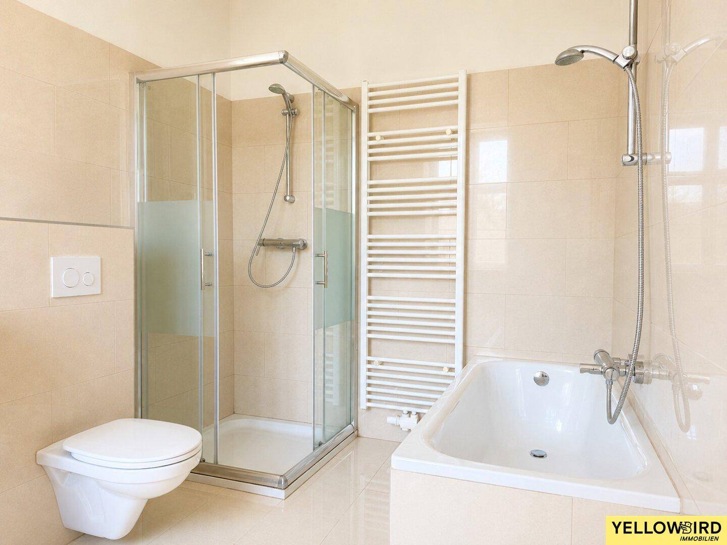 Badezimmer mit Duschkabine, Badewanne, wandhängendem WC und beheiztem Handtuchhalter.