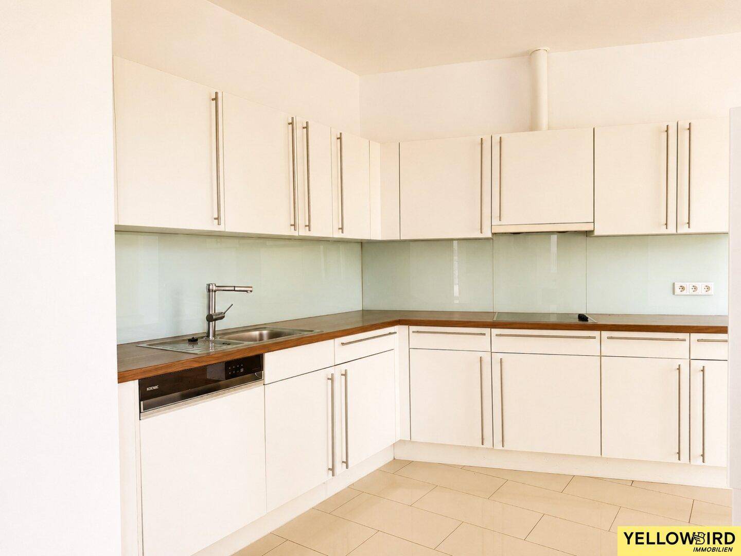 Moderne Einbauküche mit weißen Schränken, Holz-Arbeitsplatte und integriertem Geschirrspüler.