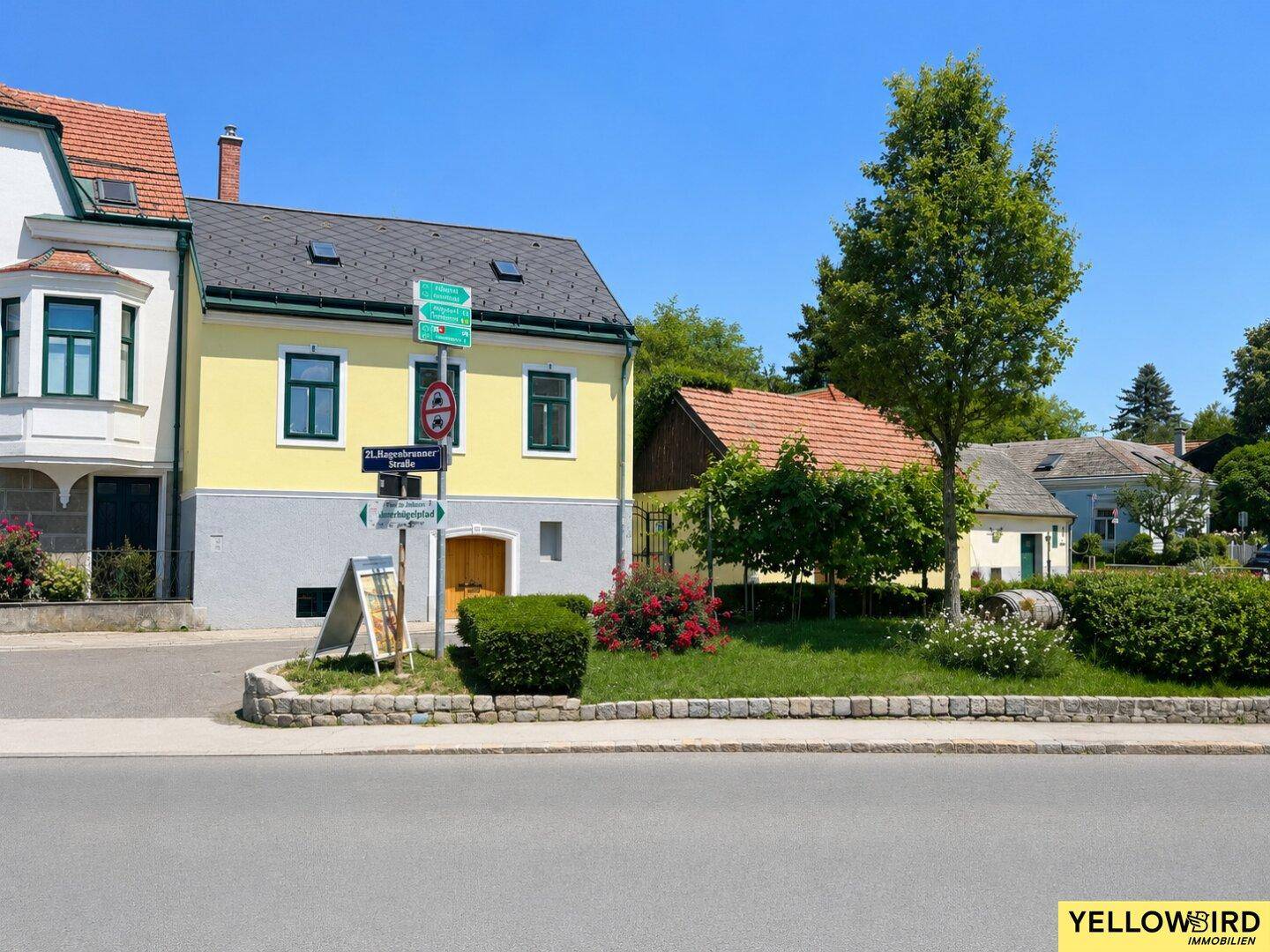 Ansicht der Straße mit umliegenden Häusern und viel Grün in einer ruhigen Wohngegend.