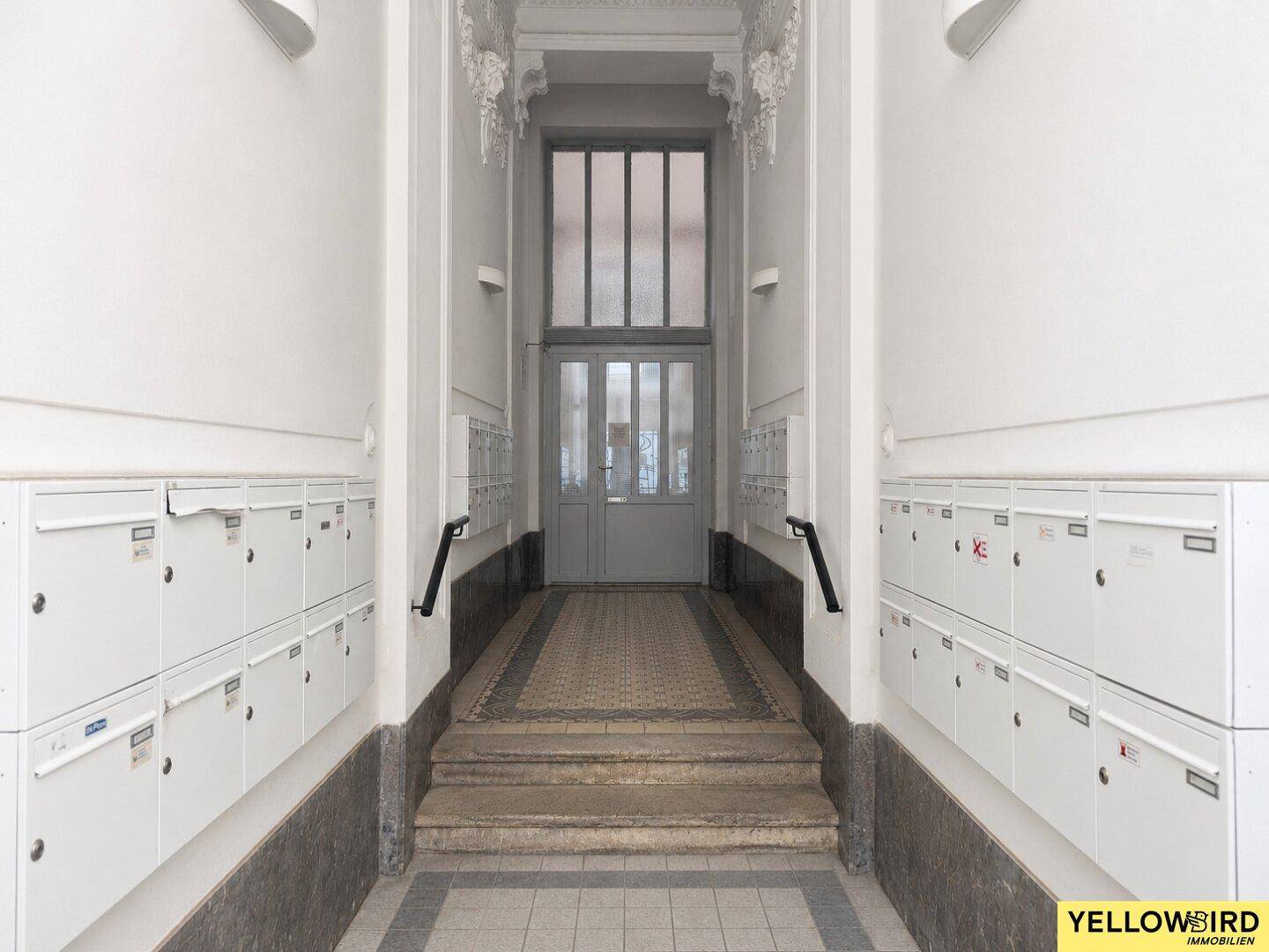 Eingangsbereich des Gebäudes mit Briefkästen und historischer Architektur.