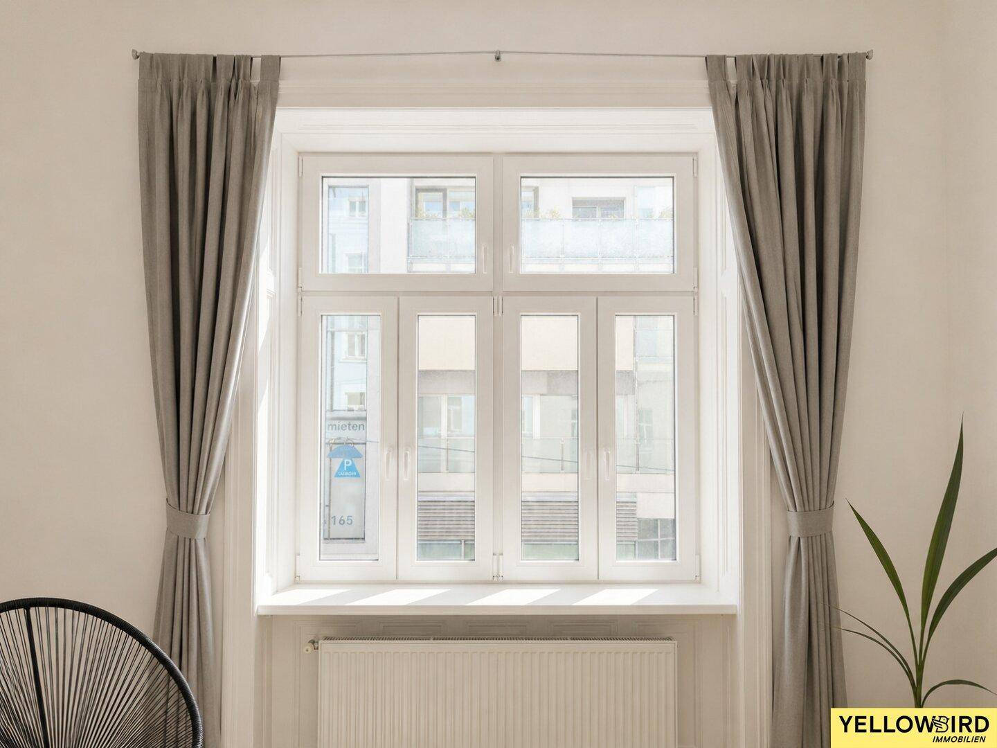 Großes Fenster mit Vorhängen und Heizkörper in einem hellen Wohnraum.