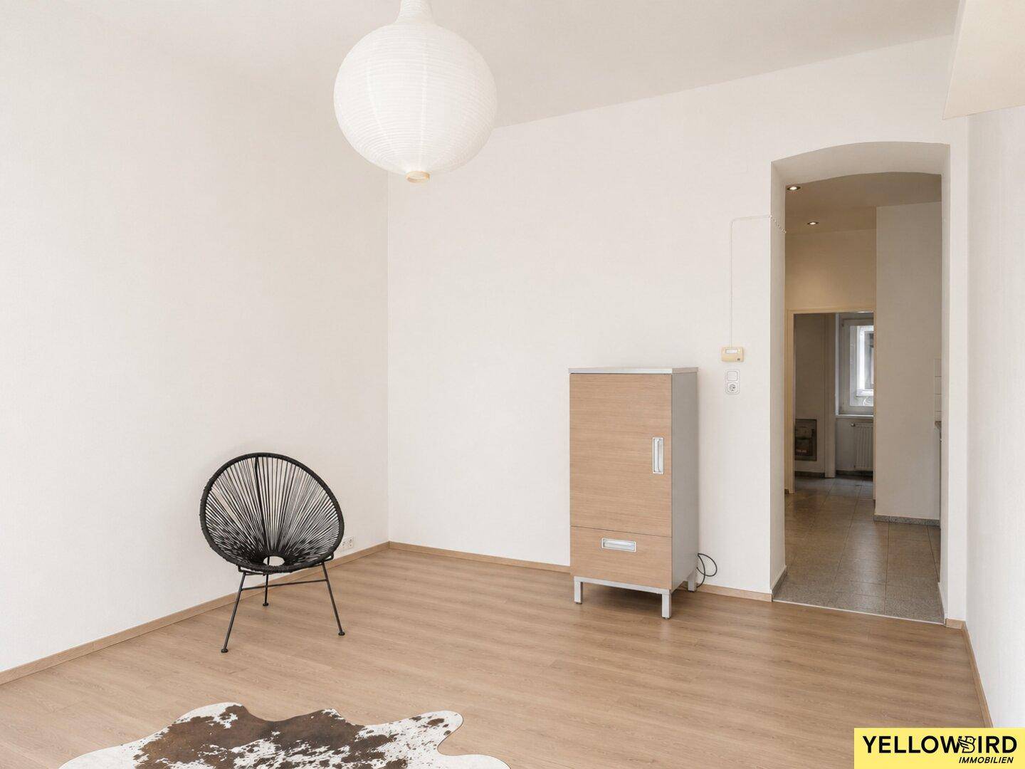 Heller Wohnraum mit Laminatboden und Durchgang zu einem weiteren Bereich.